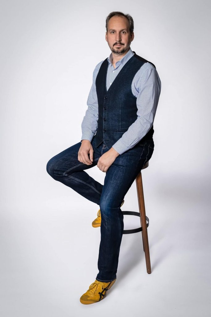 Portraitfoto von Torben Beeg im Fotostudio, sitzend auf einem Hocker