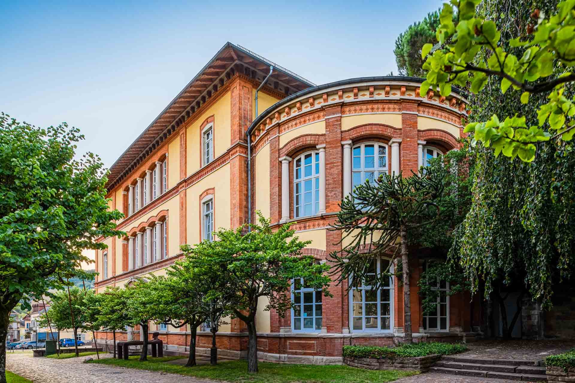 Altes Dampfbad in Baden-Baden am Marktplatz mit gelb-roter Ziegelfassade, Rundfenstern und umgebendem Grün