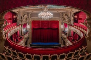 Innenansicht des Theaters Baden-Baden mit rotem Vorhang, Kronleuchter, goldener Stuckverzierung und roten Samtsitzen