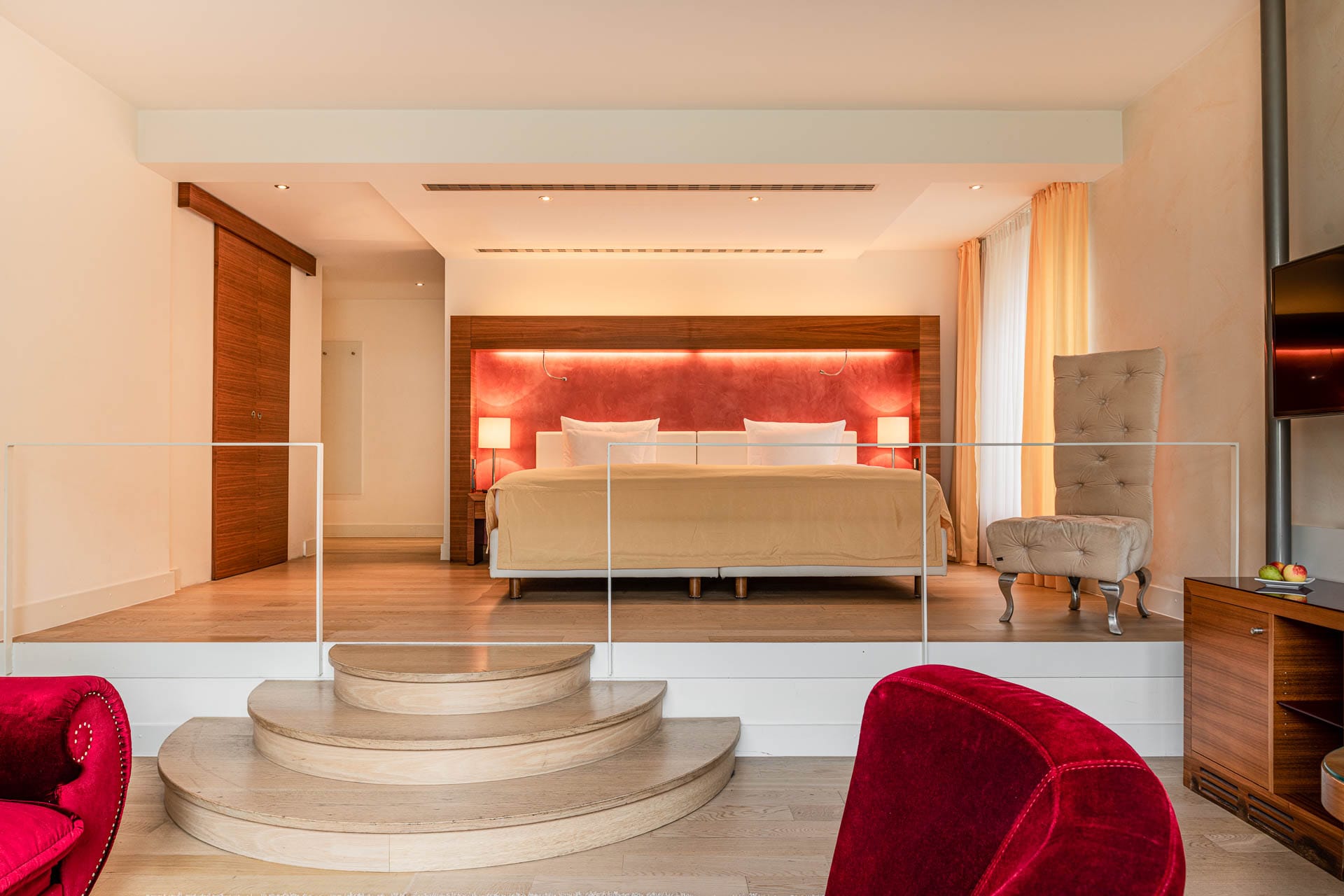 Großzügige Suite mit Podestbett, roten Akzenten und heller Einrichtung im Aqua Aurelia Suitenhotel Baden-Baden
