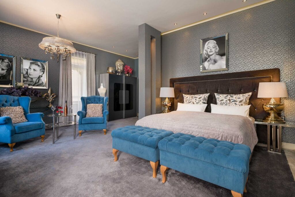 Diamant Suite – Glanzvoller Rückzugsort Villa Luise Suite Bad Bergzabern: Elegante Hotelsuite mit blauen Samtsesseln, Kristalllüster und Glamour-Dekor im Hotel Luise Bad Bergzabern
