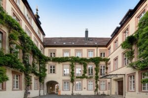 Innenhof des historischen Rathauses Baden-Baden mit gelber Fassade, grüner Fassadenbegrünung und Arkadeneingang