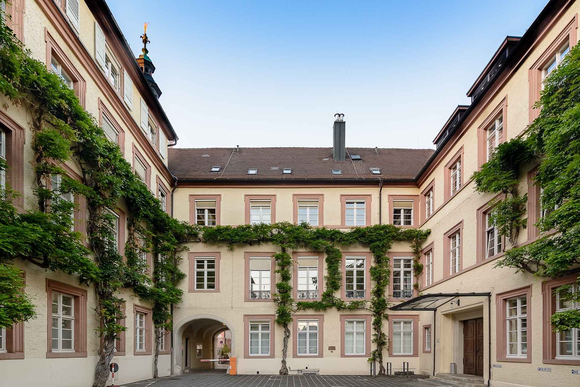 Innenhof des historischen Rathauses Baden-Baden mit gelber Fassade, grüner Fassadenbegrünung und Arkadeneingang