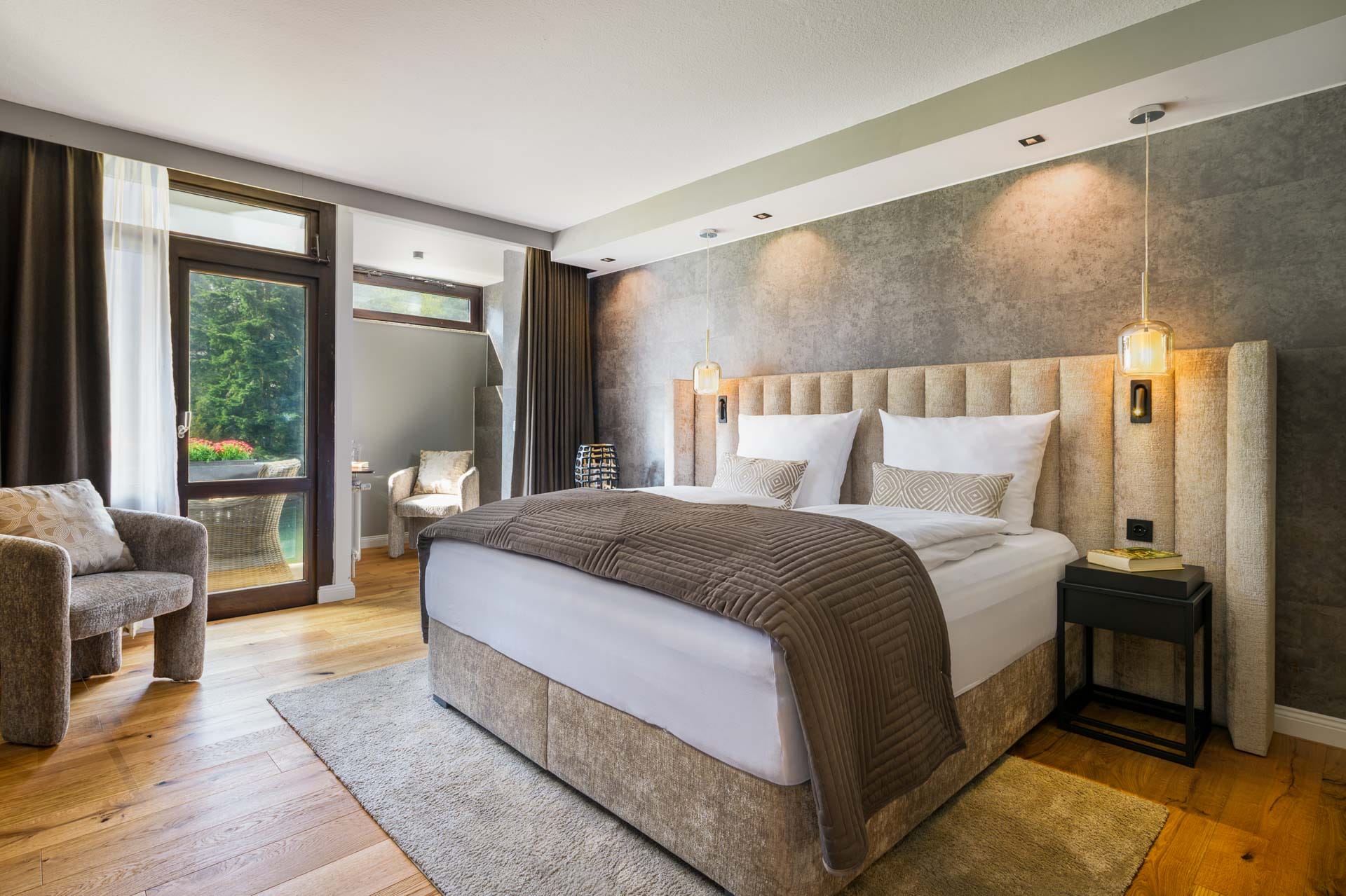Modern eingerichtetes Komfort Doppelzimmer mit gepolstertem Kopfteil, warmen Naturtönen und Ausblick ins Grüne im Hotel Luisenpark Bad Bergzabern