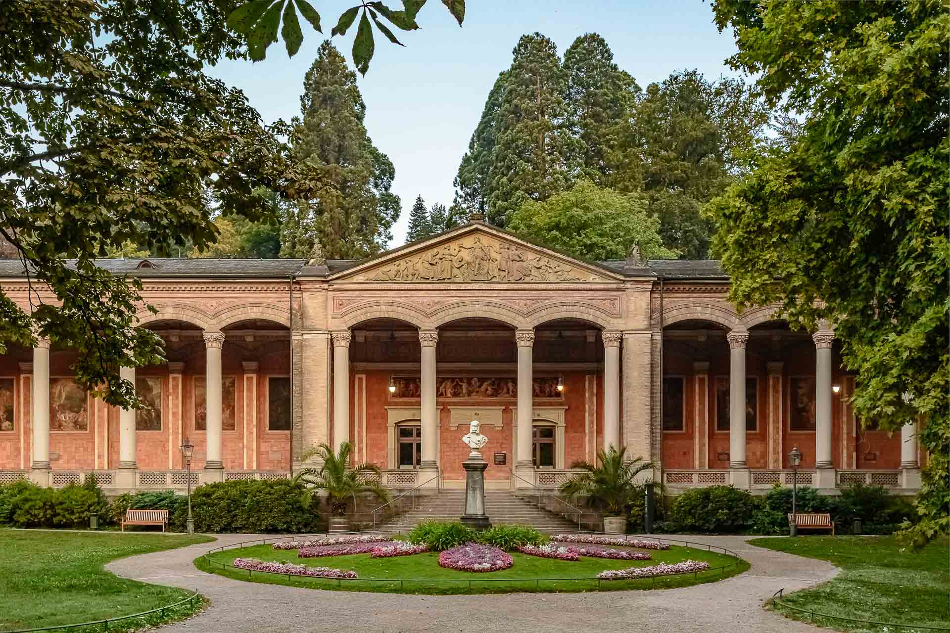 Historischer Arkadengang der Trinkhalle in Baden-Baden mit Säulen, Fresken und Brunnen im Vordergrund